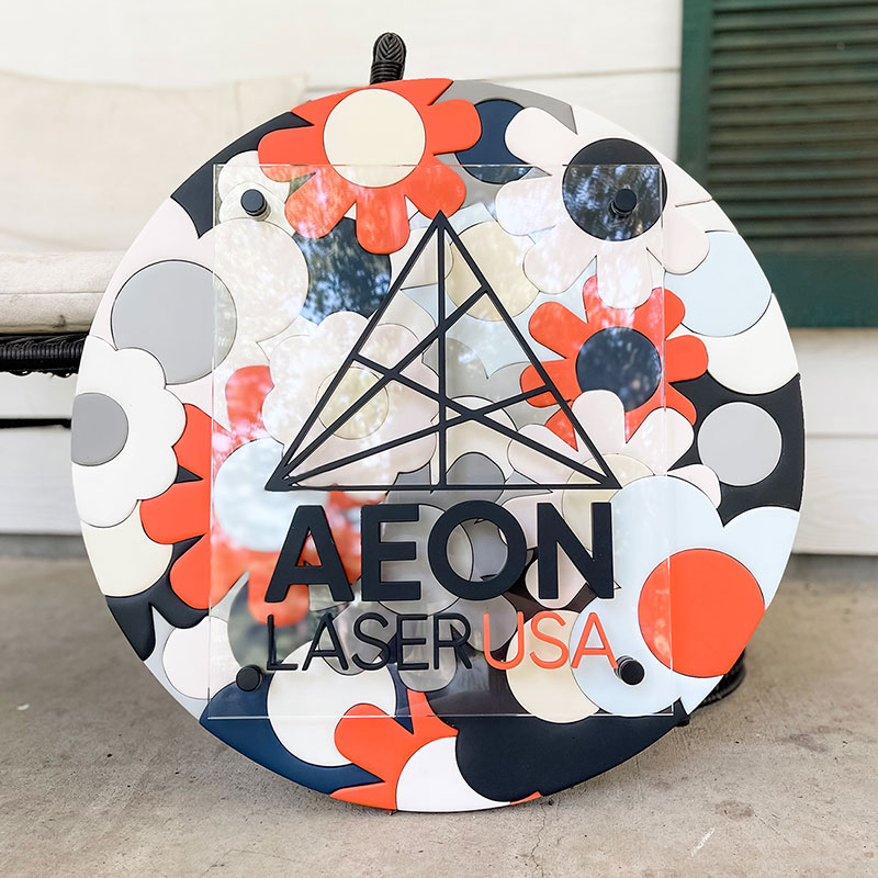 round wooden sign made of orange, blue, and white flowers with a prism and 粗暴调教玩弄np高h小说 logo on top