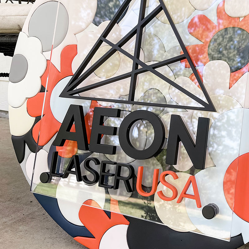 round wooden sign made of orange, blue, and white flowers with a prism and 粗暴调教玩弄np高h小说 logo on top
